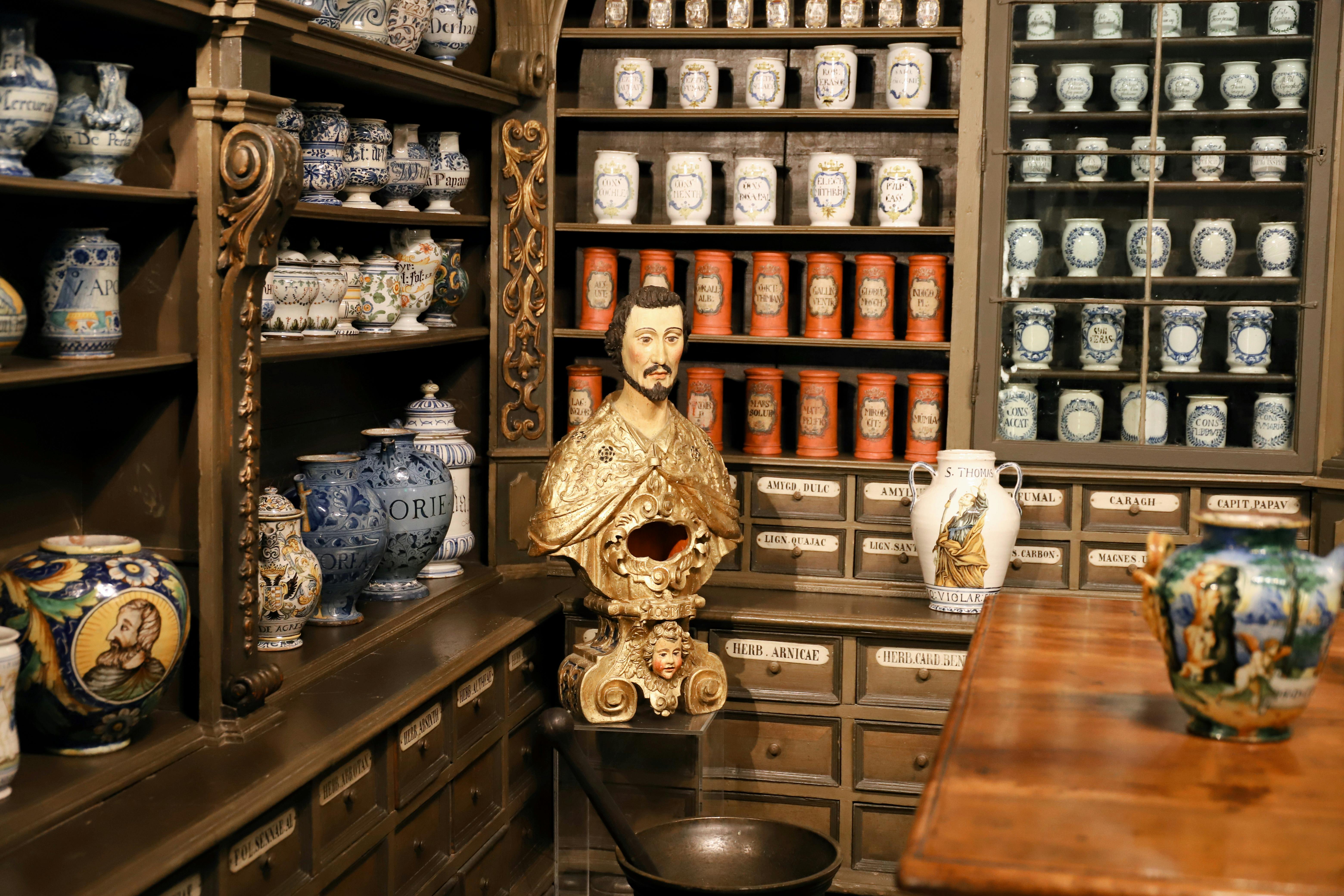 Présentoir d'apothicaire du 18e siècle au Musée allemand de la pharmacie à Heidelberg, avec des rangées de pots en céramique étiquetés et un buste doré
